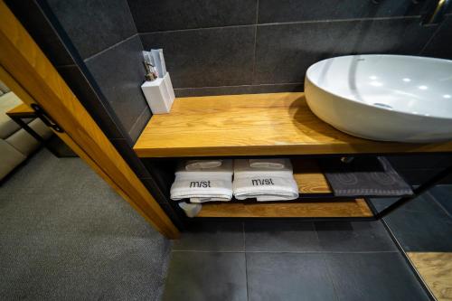 ein Badezimmer mit Waschbecken und Handtüchern auf einem Regal in der Unterkunft MIST Boutique Hotel in Yerevan