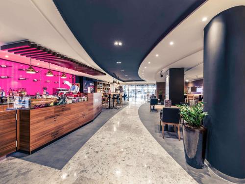a restaurant with a bar with pink lighting at Mercure Budapest City Center in Budapest