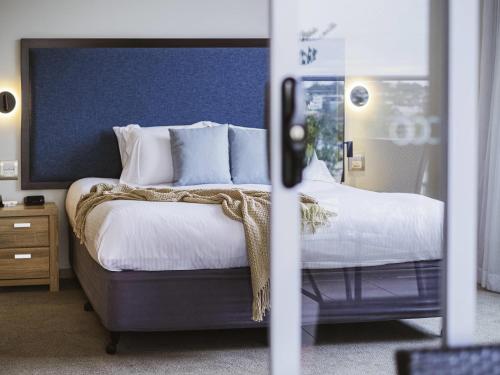a bedroom with a bed with white sheets and pillows at Mercure Centro Port Macquarie in Port Macquarie