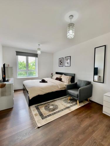 a white bedroom with a bed and a chair at Stay in Stratford in London