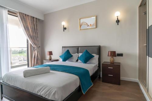 a bedroom with two beds with blue pillows and a window at Spectacular 3 bedroom apartment in Syokimau