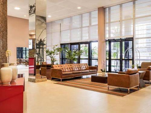 a lobby with a couch and chairs and windows at Mercure Salvador Boulevard Hotel in Salvador