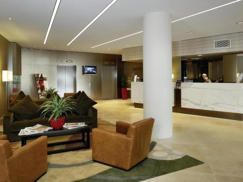 a lobby with a couch and a table and chairs at Novotel Sydney West HQ in Rooty Hill