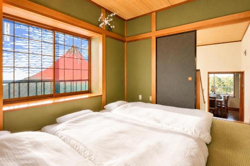 two white beds in a room with a window at Fuji Nest Izu in Izunokuni