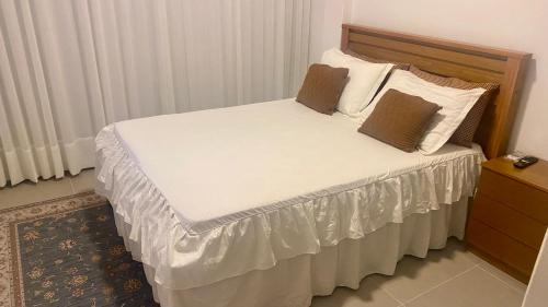 a bedroom with a bed with white sheets and pillows at Elegância Praia da Sereia in Vila Velha