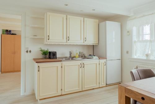 a kitchen with white cabinets and a sink at Jógvansstova - 2BR House - Explore the North in Leirvík