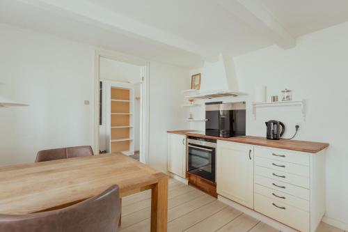 a kitchen with white cabinets and a wooden table at Jógvansstova - 2BR House - Explore the North in Leirvík