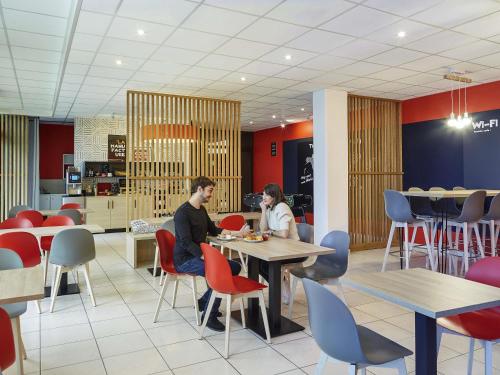two people sitting at tables in a restaurant at Aparthotel Adagio Access Avignon in Avignon