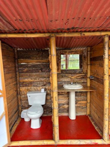 a bathroom with a toilet and a sink in a log cabin at Camping El Paraiso in Calima