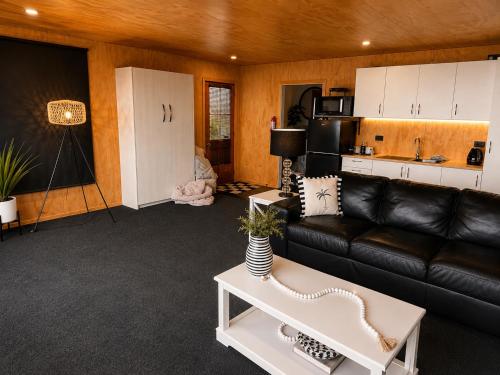 a living room with a black leather couch and a table at Lake Brunner Chalet in Moana