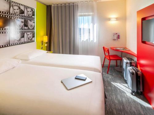 a hotel room with two beds and a desk at ibis Styles Cannes Le Cannet in Cannes
