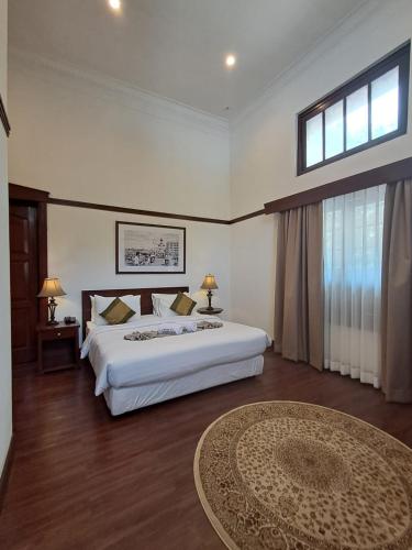 a bedroom with a large white bed and a table at Hotel Butik Sawunggaling in Bandung