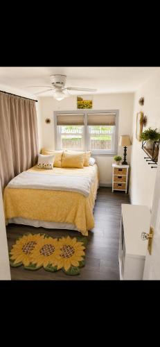 a bedroom with a large bed with yellow sheets and two windows at The sunflower stay in Garden City