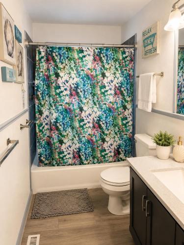 a bathroom with a shower with a large flower shower curtain at The sunflower stay in Garden City