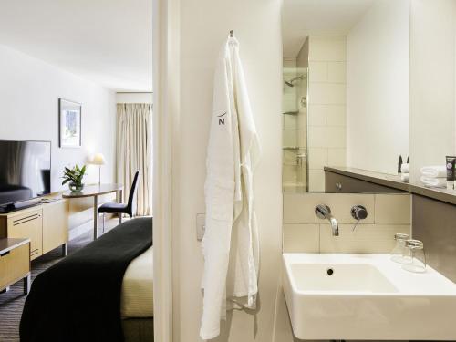 a hotel room with a sink and a bedroom at Novotel Queenstown Lakeside in Queenstown