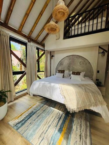 a bedroom with a large bed in a room with windows at FINCA HOTEL GUADUAL Quindío in Quimbaya