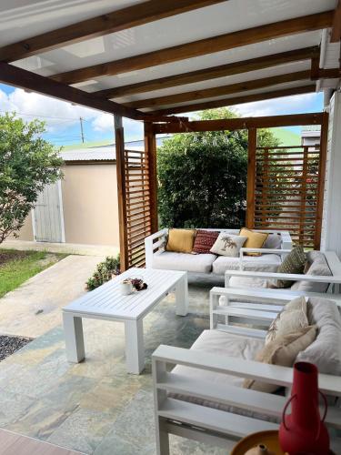 a patio with white tables and couches under a pergola at Villa Odeyssia in Sainte-Anne