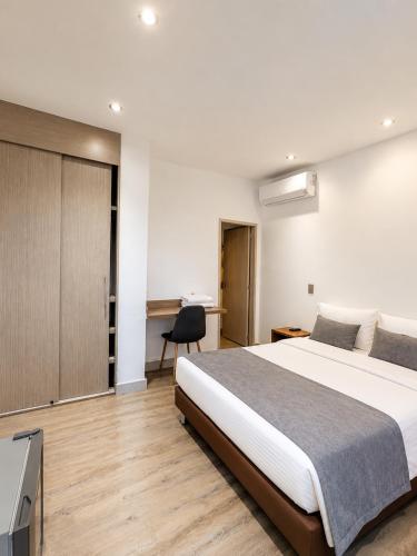 a bedroom with a large bed and a desk at Hotel Laureles Loft in Medellín