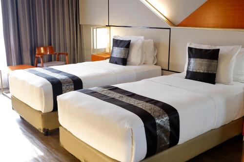 two beds in a hotel room with white and black sheets at Rayz UMM Hotel Malang in Malang