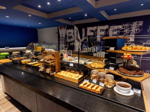 a buffet line with various types of bread and pastries at ibis budget Curitiba Centro in Curitiba