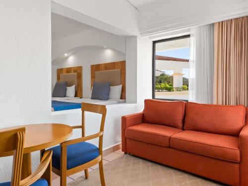 a living room with a couch and a table and a bed at Park Royal Beach Huatulco in Tangolunda