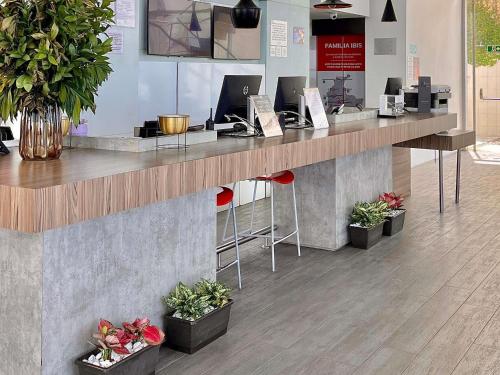 a lobby with a reception counter with potted plants at ibis Cartagena Marbella in Cartagena de Indias