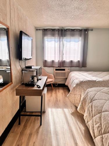 a bedroom with a bed and a desk with a television at Confederation Inn Saskatoon in Saskatoon