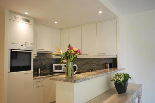 une cuisine avec un vase de fleurs sur un comptoir dans l'établissement 1 Bedroom Apartment - Les Jardins de la Croisette, à Cannes
