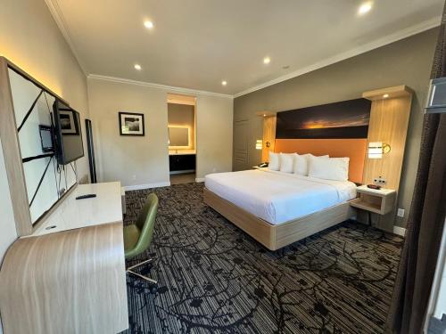 a hotel room with a bed and a flat screen tv at Granada Inn in Granada Hills