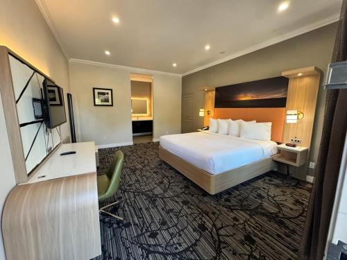 a hotel room with a bed and a flat screen tv at Granada Inn in Granada Hills