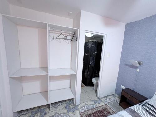 a bedroom with white shelves and a bathroom with a toilet at Hotel Simon II in Antofagasta