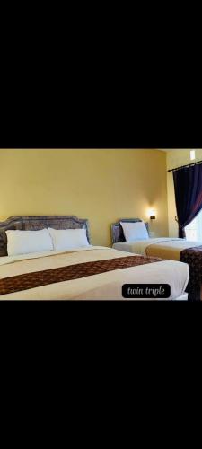 two beds in a hotel room with a sign on it at Griya Imafa Inn Batu in Tlekung