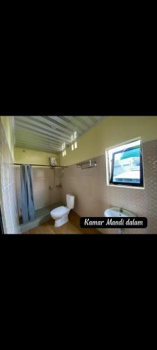 a bathroom with a toilet and a tv on the wall at Griya Imafa Inn Batu in Tlekung