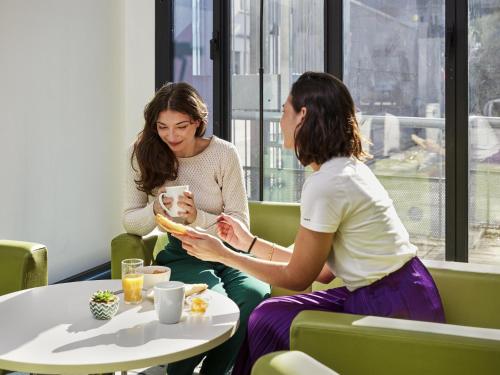 two women sitting at a table eating food at Aparthotel Adagio Access Paris Bastille in Paris