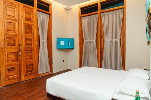 a bedroom with a bed and wooden doors at Acasa Cottage by Samsara in Cipaok