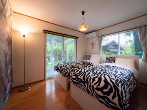 a bedroom with two beds with zebra print sheets at みどりの風 -那須高原中心地-森を感じる貸切一軒家-観光や買い物に便利-無料bbq-最大7名-子供歓迎 in Nasu