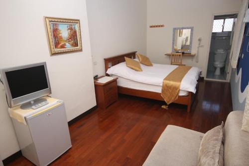 a small bedroom with a bed and a television at Sunrise B&B in Huxi