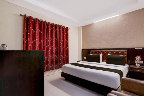 a bedroom with a large bed and red curtains at Collection O Haridwar Railway Station Formerly Le Central in Haridwār