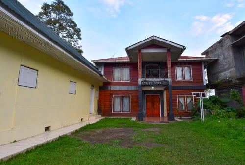 a red and yellow house with a red door at Maya Sari Cottage Pandai Sikek in Kotabaru