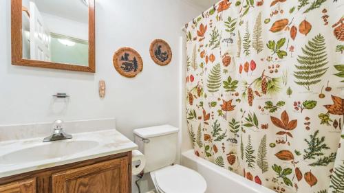 a bathroom with a toilet and a shower curtain with leaves at Arena by AvantStay in North Creek