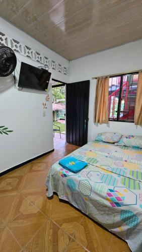 a bedroom with a bed and a flat screen tv at El Cacique Villeta Hostal in Villeta