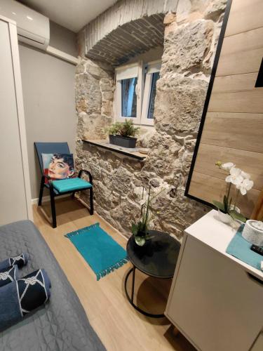 a room with a stone wall and a bed and a table at Apartman Barocco Lovran in Lovran