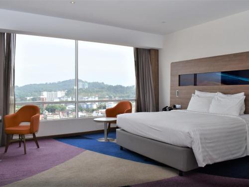 a hotel room with a bed and a large window at Novotel Taiping in Taiping