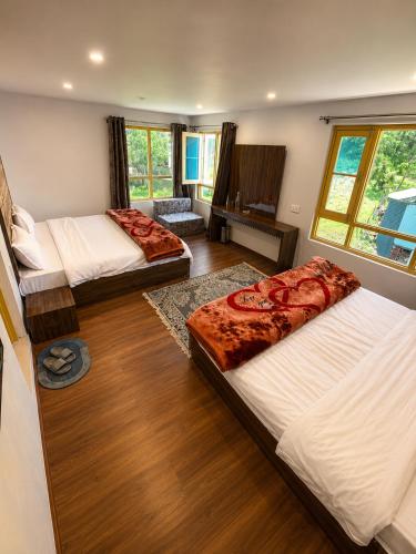 a bedroom with two beds and a living room at THE NUN KUN Pahalgam in Pahalgām