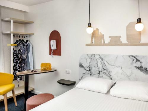 a bedroom with a bed and a desk and a table at Hôtel ibis Styles Vichy Centre in Vichy