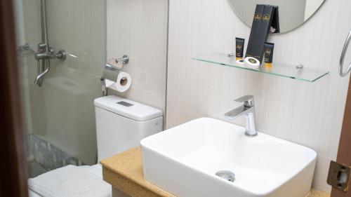 a bathroom with a sink and a toilet and a mirror at Emmie Hotel in Legazpi