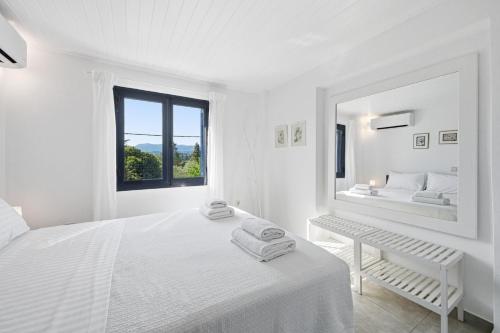 a white bedroom with a white bed and a mirror at The Garden Maisonette in Gouvia