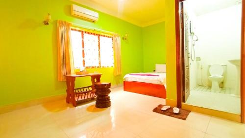 a green room with a bed and a mirror at Sam So Guesthouse in Siem Reap