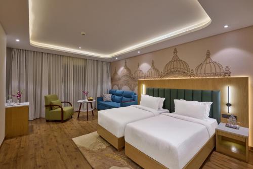 a bedroom with a large bed and a blue couch at Regenta Devarayah Tirupati in Tirupati