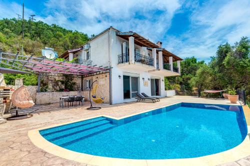 a villa with a swimming pool in front of a house at Daniella with Seaview Pool in Nisaki